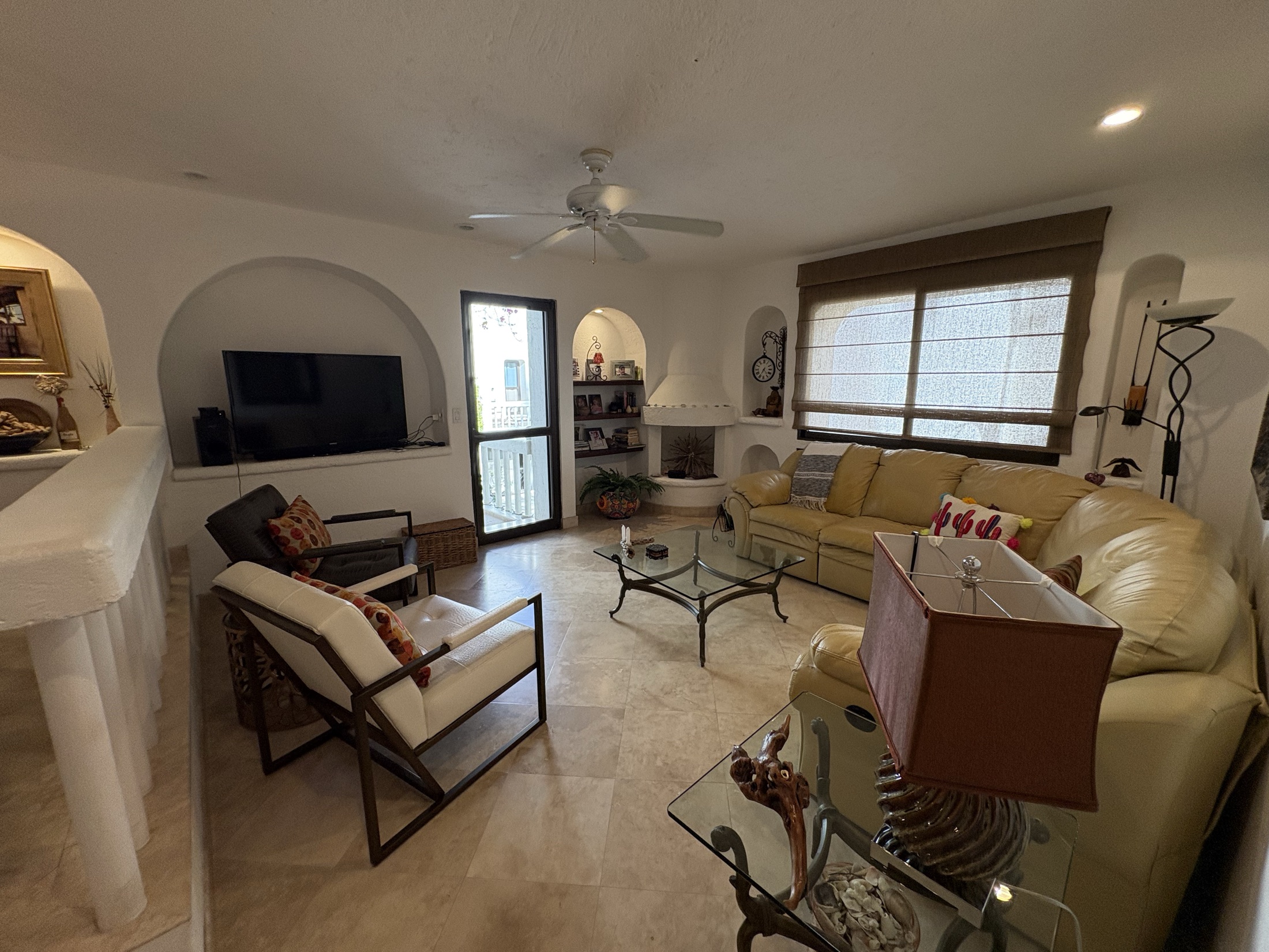 Dining and living area with white railing and travertine floors