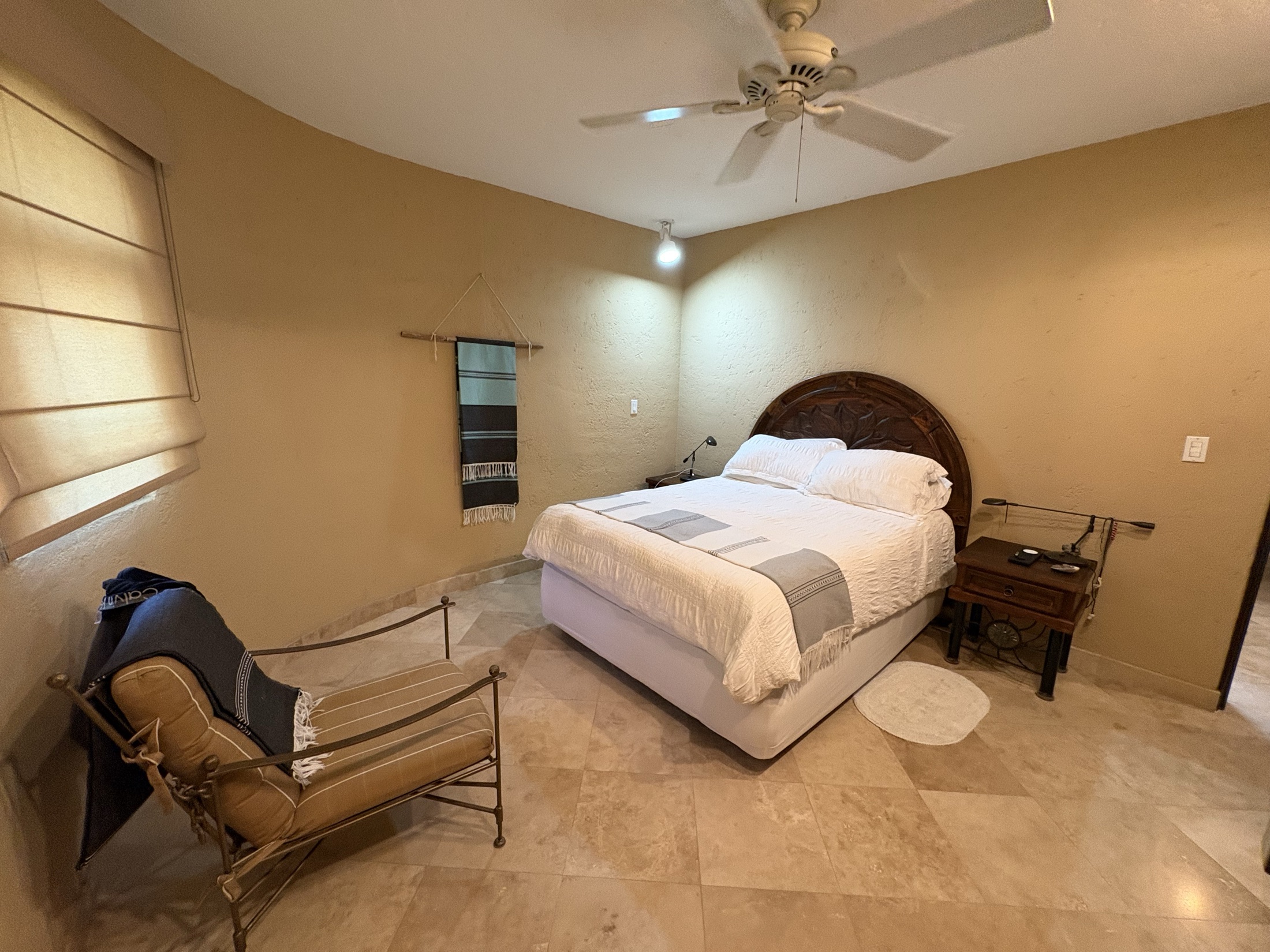 Second bedroom with warm wall color, bed, side table, and chair